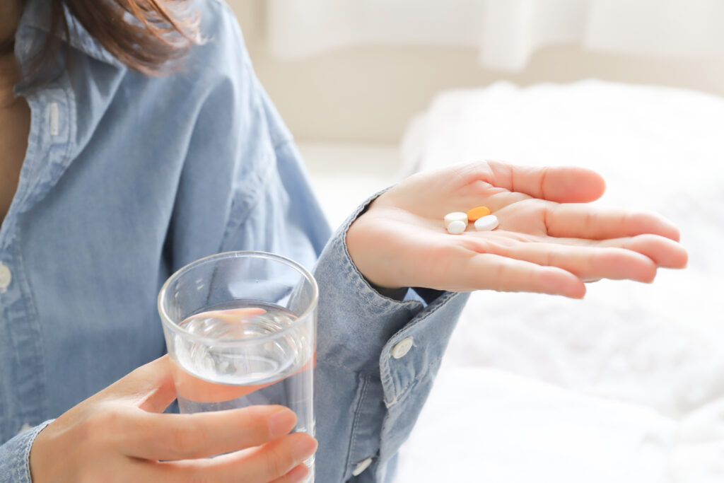 根管治療後の痛みを和らげるために薬を飲む女性