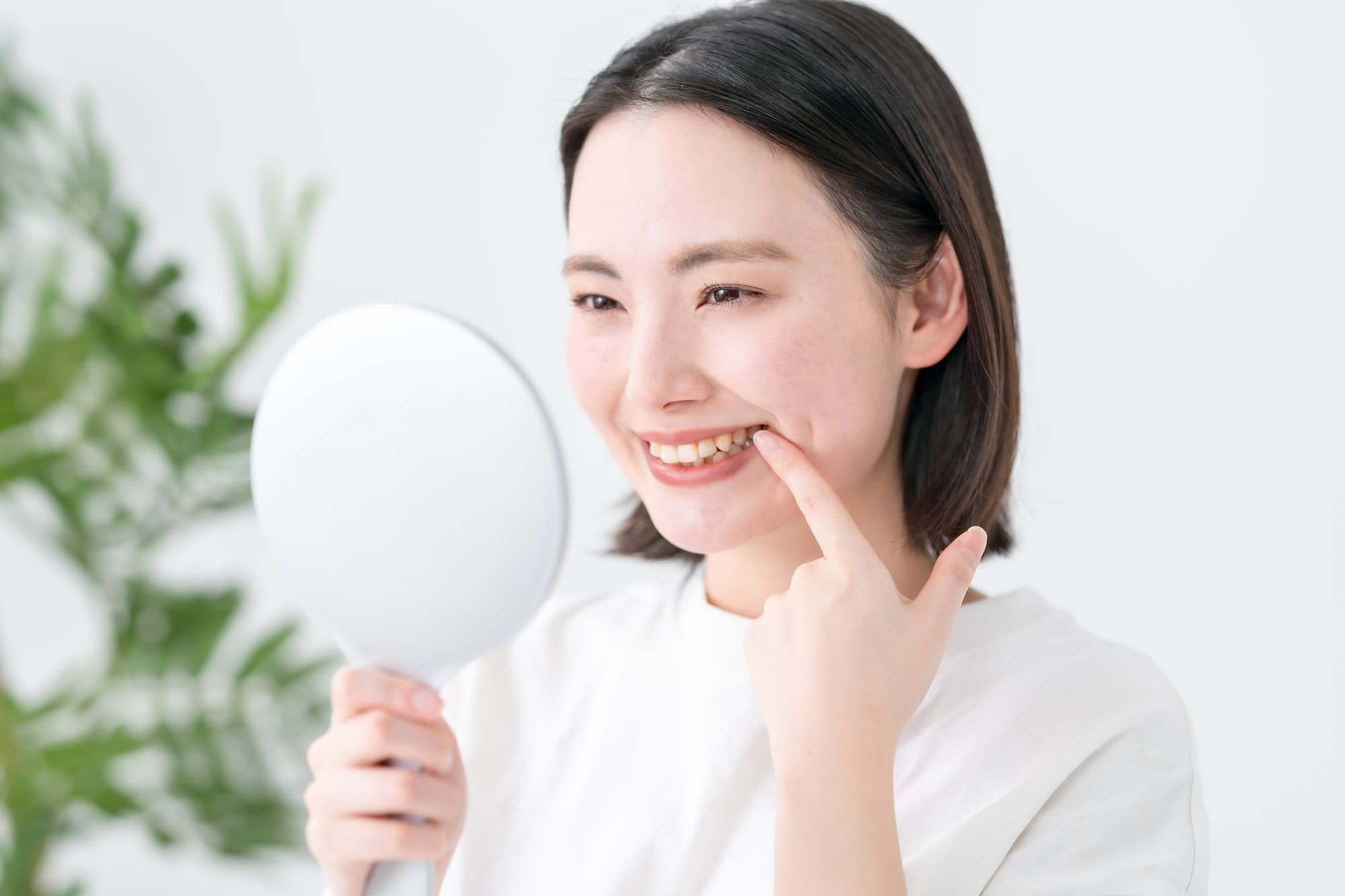 綺麗になった歯茎を鏡で確認する女性