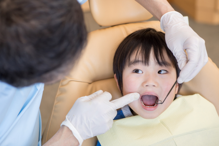 虫歯を治療するため歯科医院で診察してもらう子ども