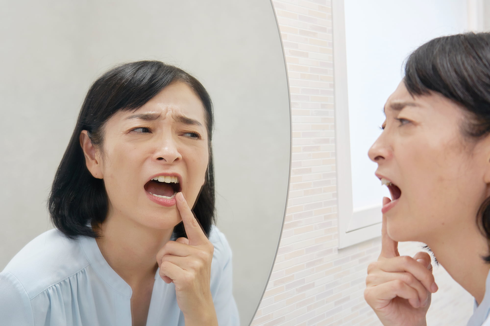 セラミック治療に満足できず鏡で歯を見る女性