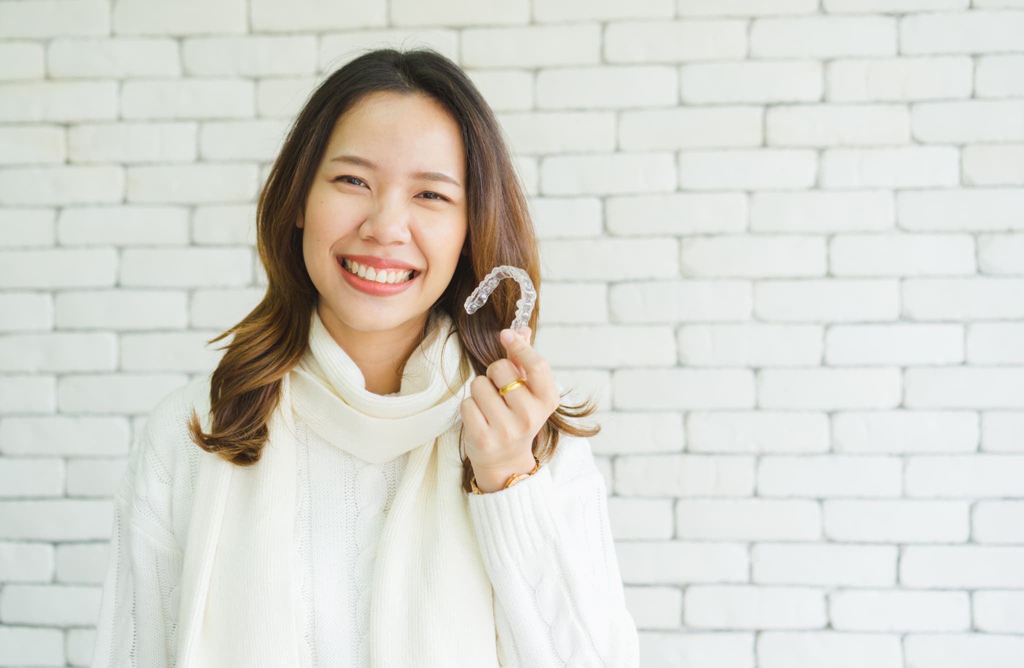 マウスピースを持って笑顔を見せる女性