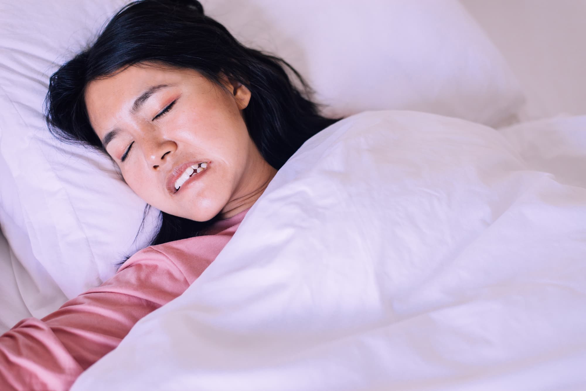 就寝中に歯ぎしりをする女性